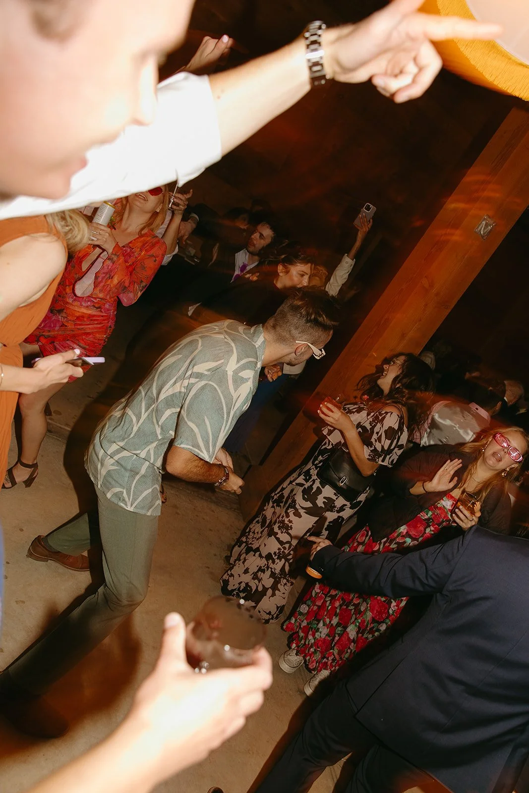 Guests dance energetically at the indoor reception, with motion blur capturing the energy of the dance floor.