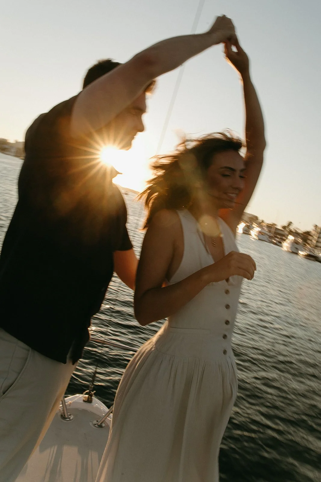 Motion blur photo of a couple dancing on the sailboat with the sun shining in between them during their sailboat engagement photos.