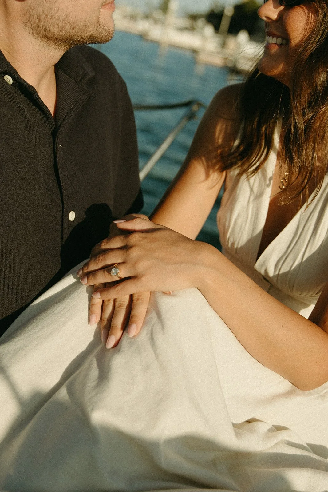 Close-up of an engagement ring as couple holds hands on a sailboat, sunset sailboat engagement photos highlighting their connection.