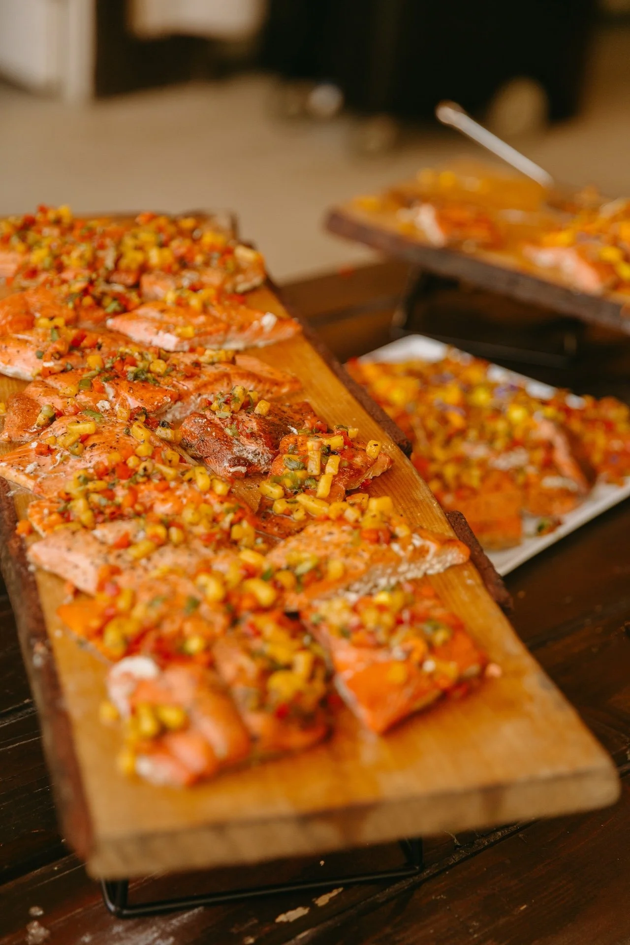 Fresh salmon topped with mango salsa displayed on wooden boards at the garden party wedding reception dinner.