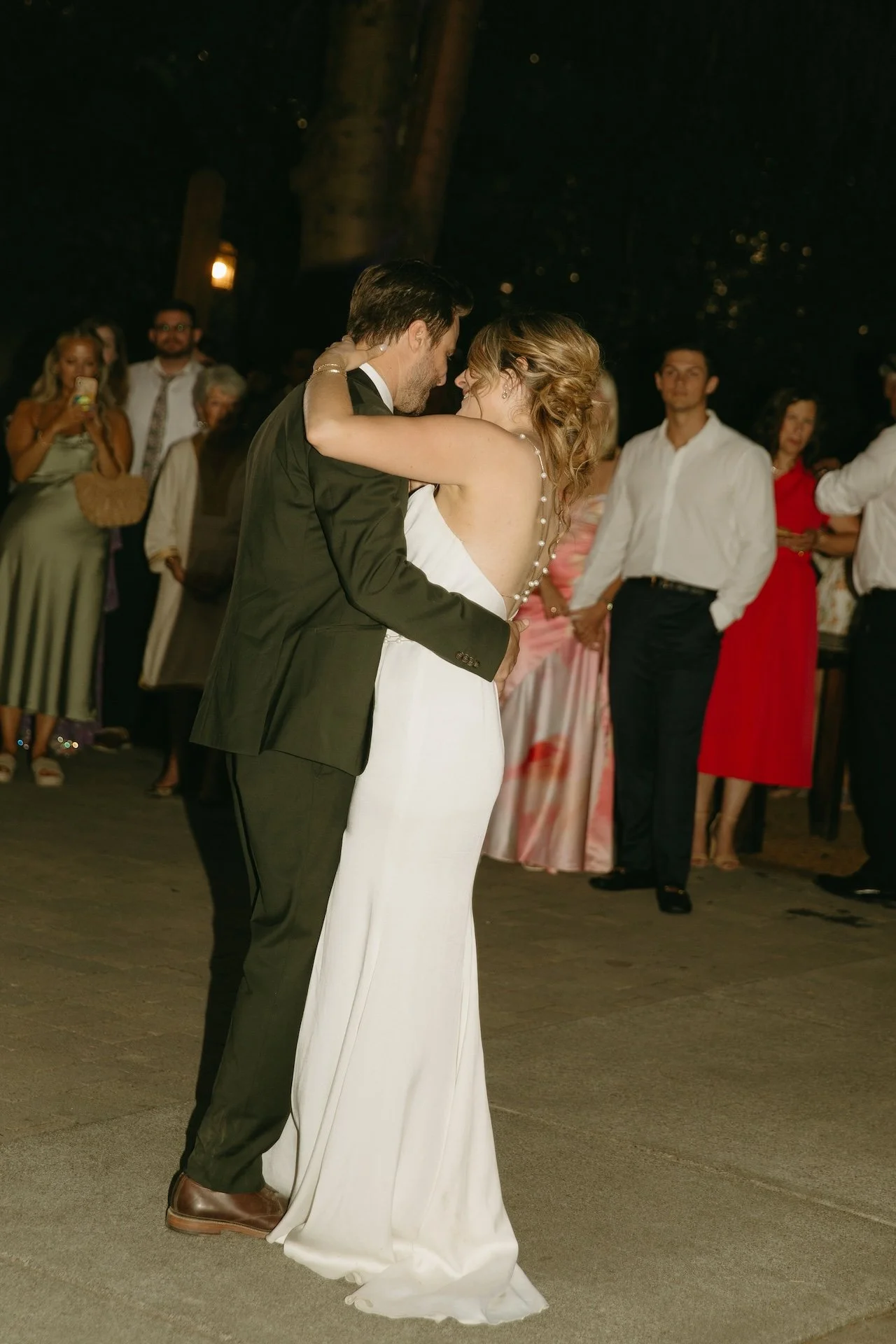 Bride and groom share their first dance at the reception surrounded by friends and family.