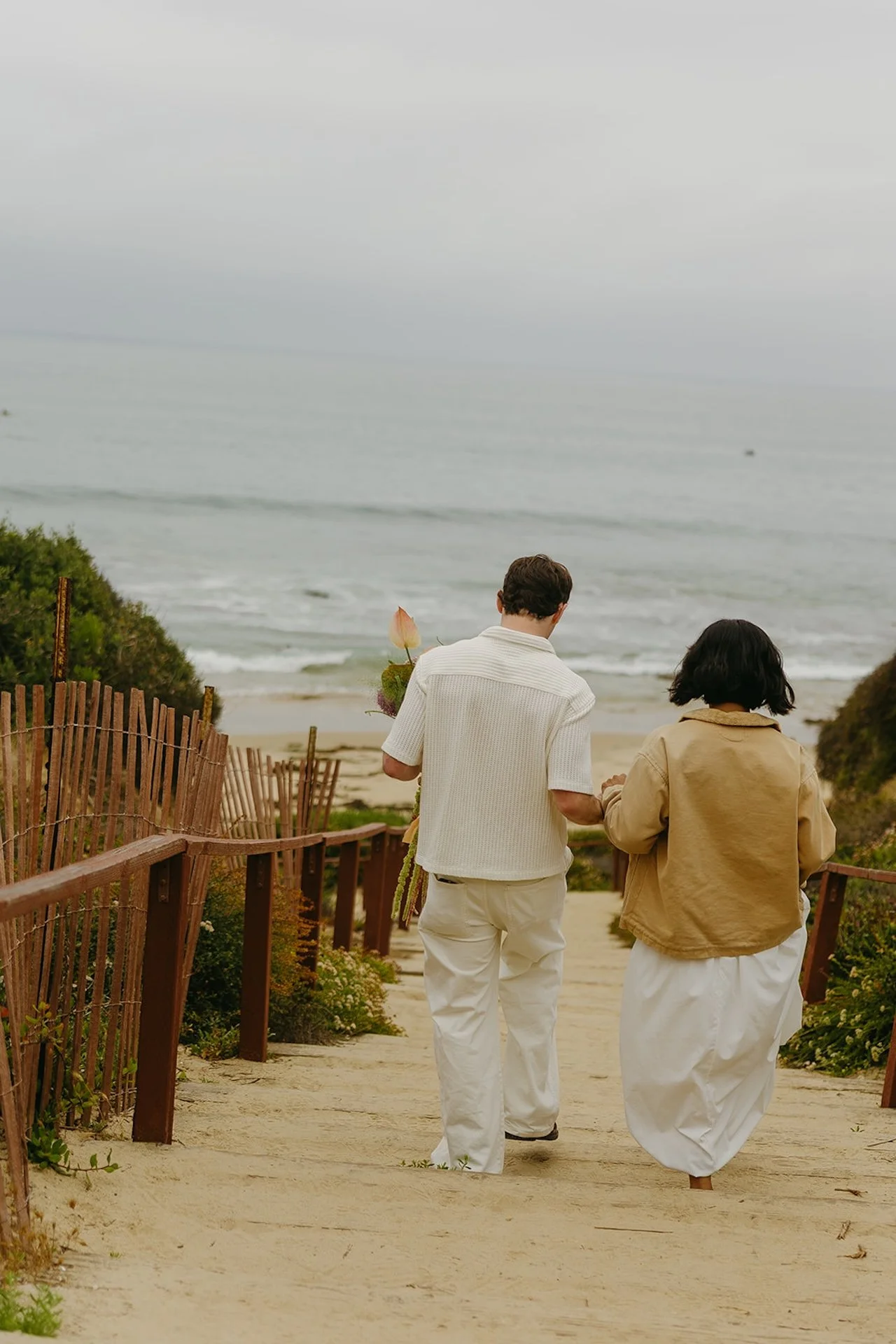 Bride and groom walking down wooden stairs to the beach for their elopement on the beach