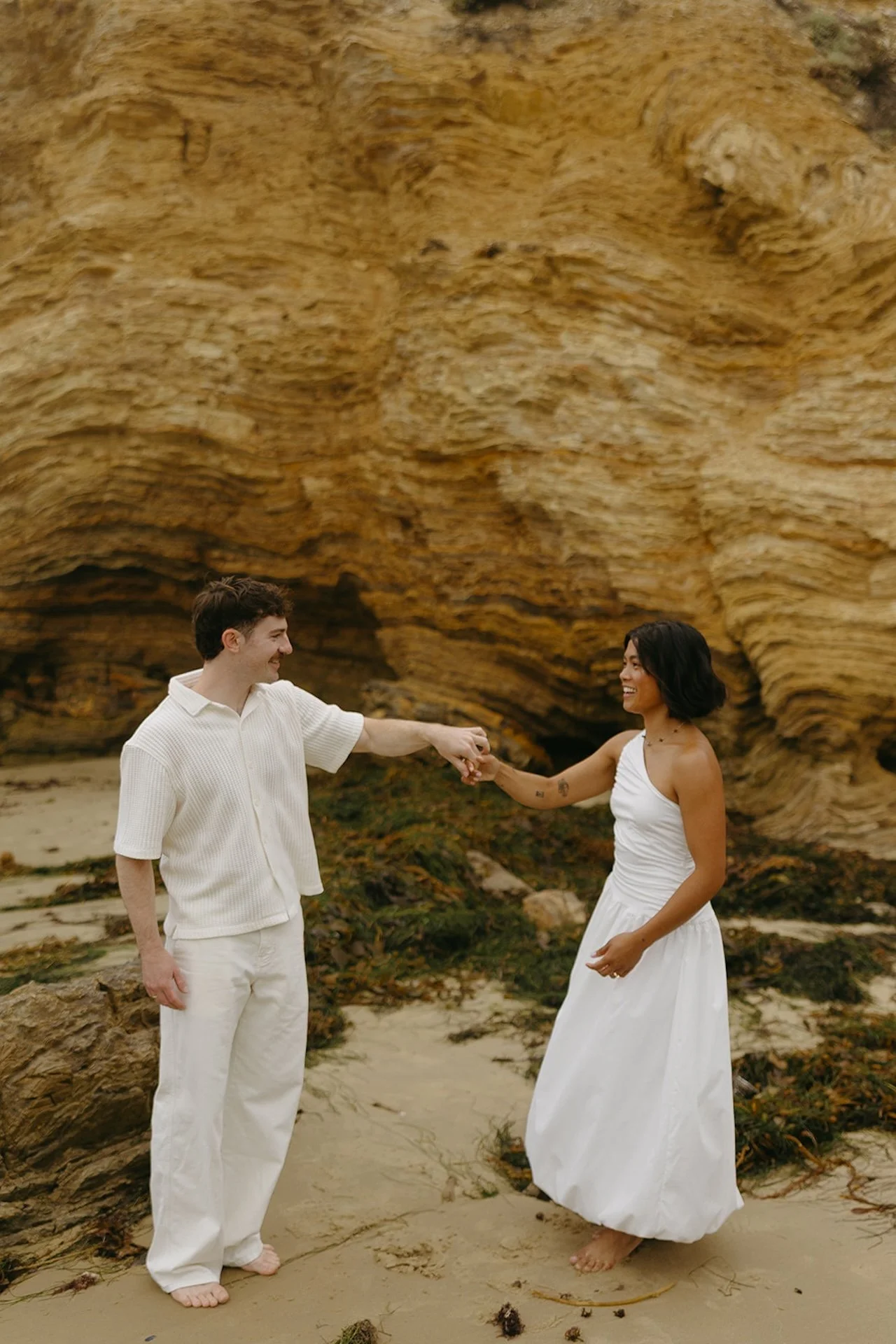 The bride and groom dancing on the beach with the beach cliffs behind them