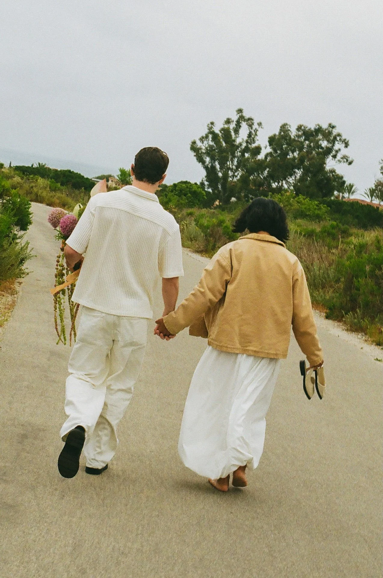 The bride and groom walking down the path along the coast to get to the beach for their laguna beach elopement