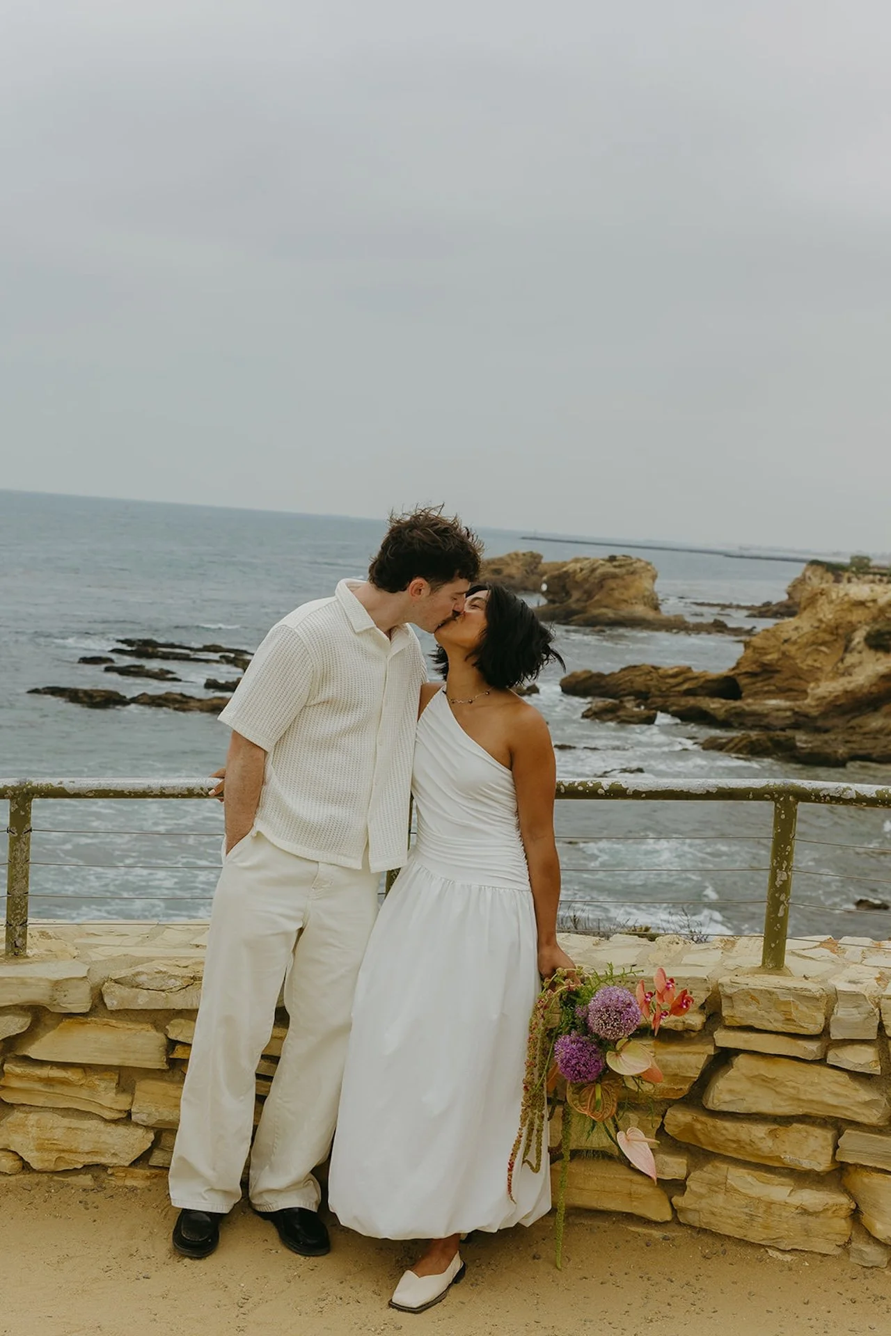 The bride and groom kissing after their elopement ceremony during their beach elopement