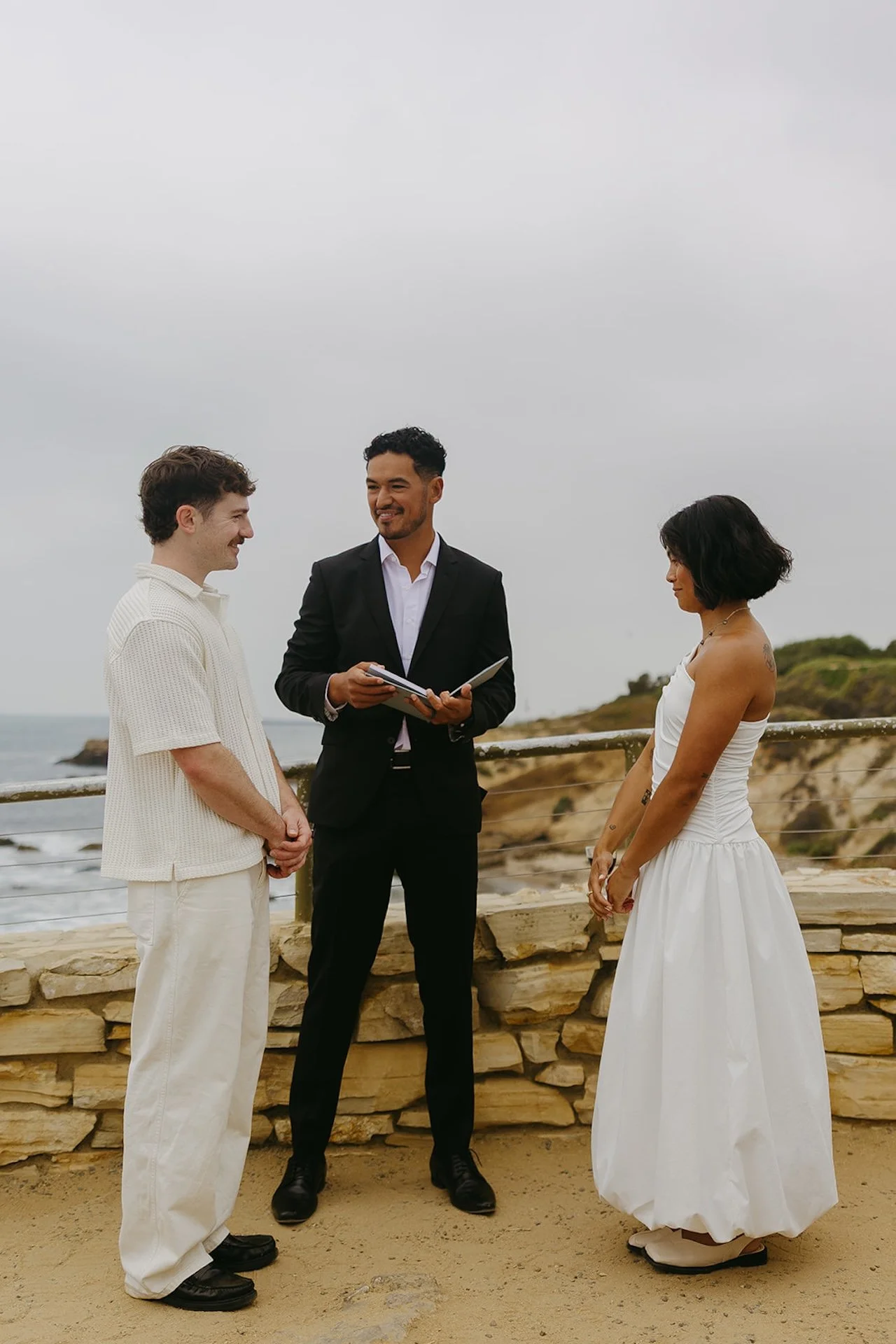 The bride and groom standing with the officiant during their elopement ceremony