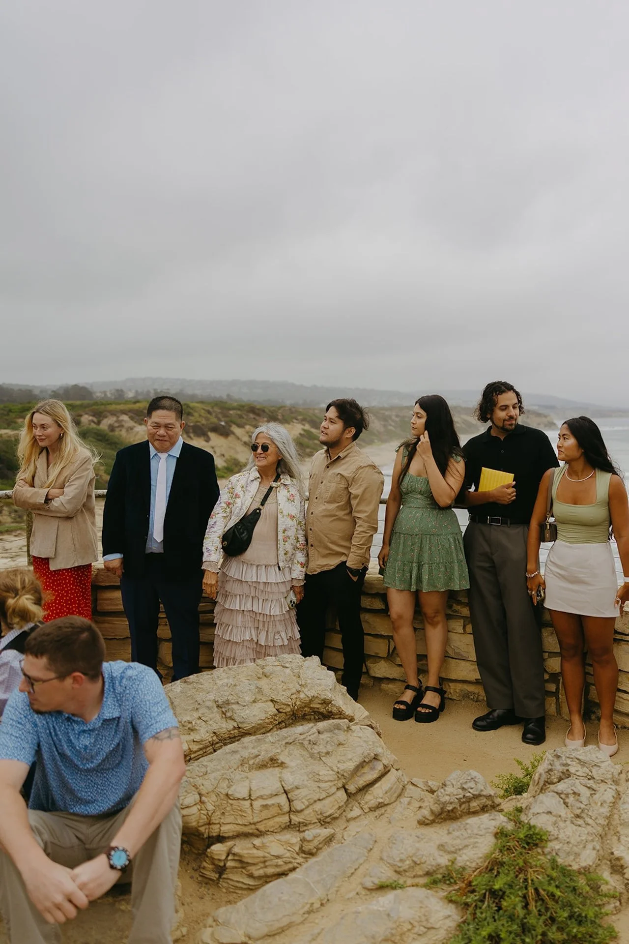 Wedding guests smiling gathered around watching the ceremony of the elopement on the beach