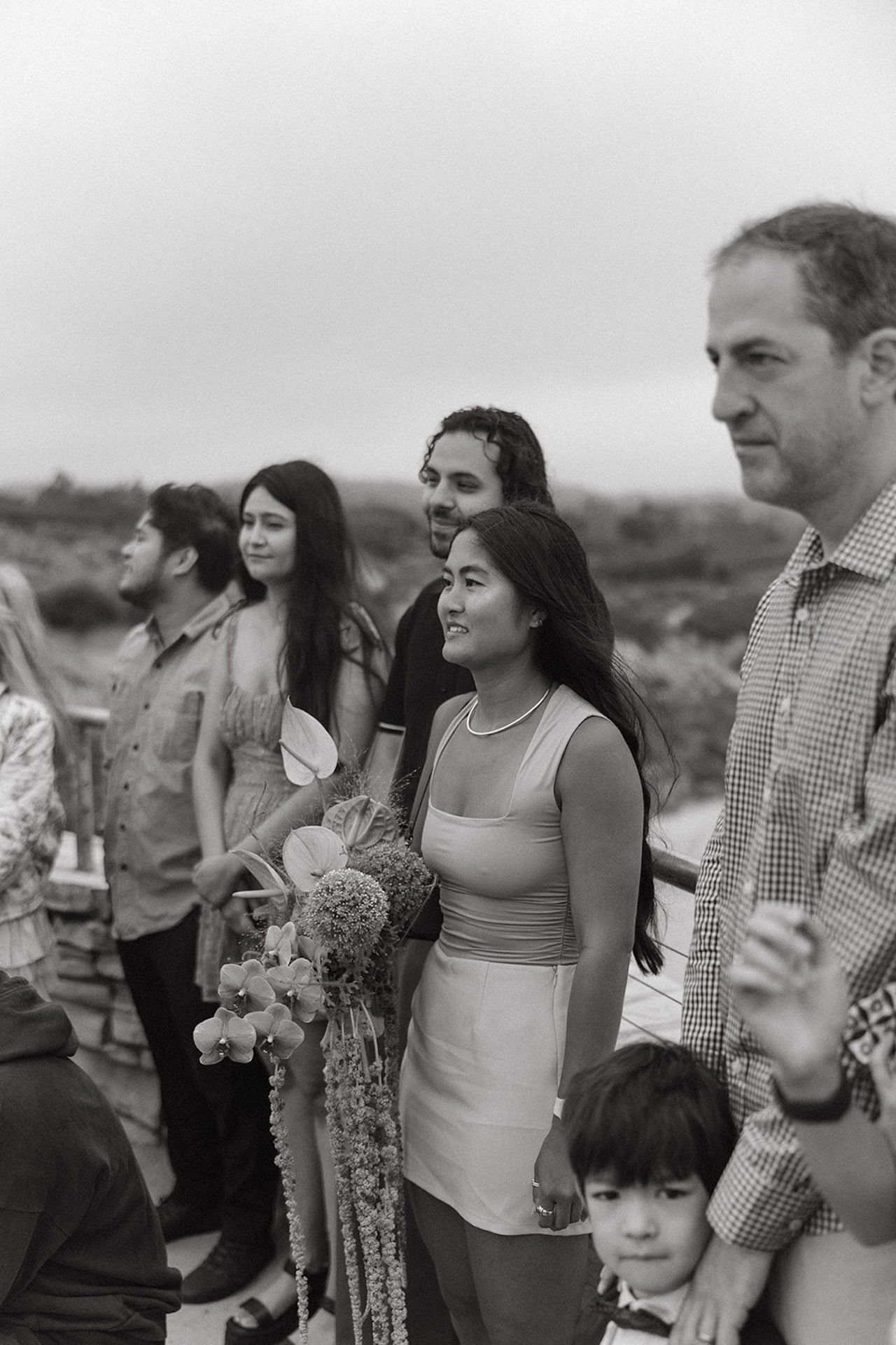 Wedding guests gathered around watching the ceremony of the elopement on the beach