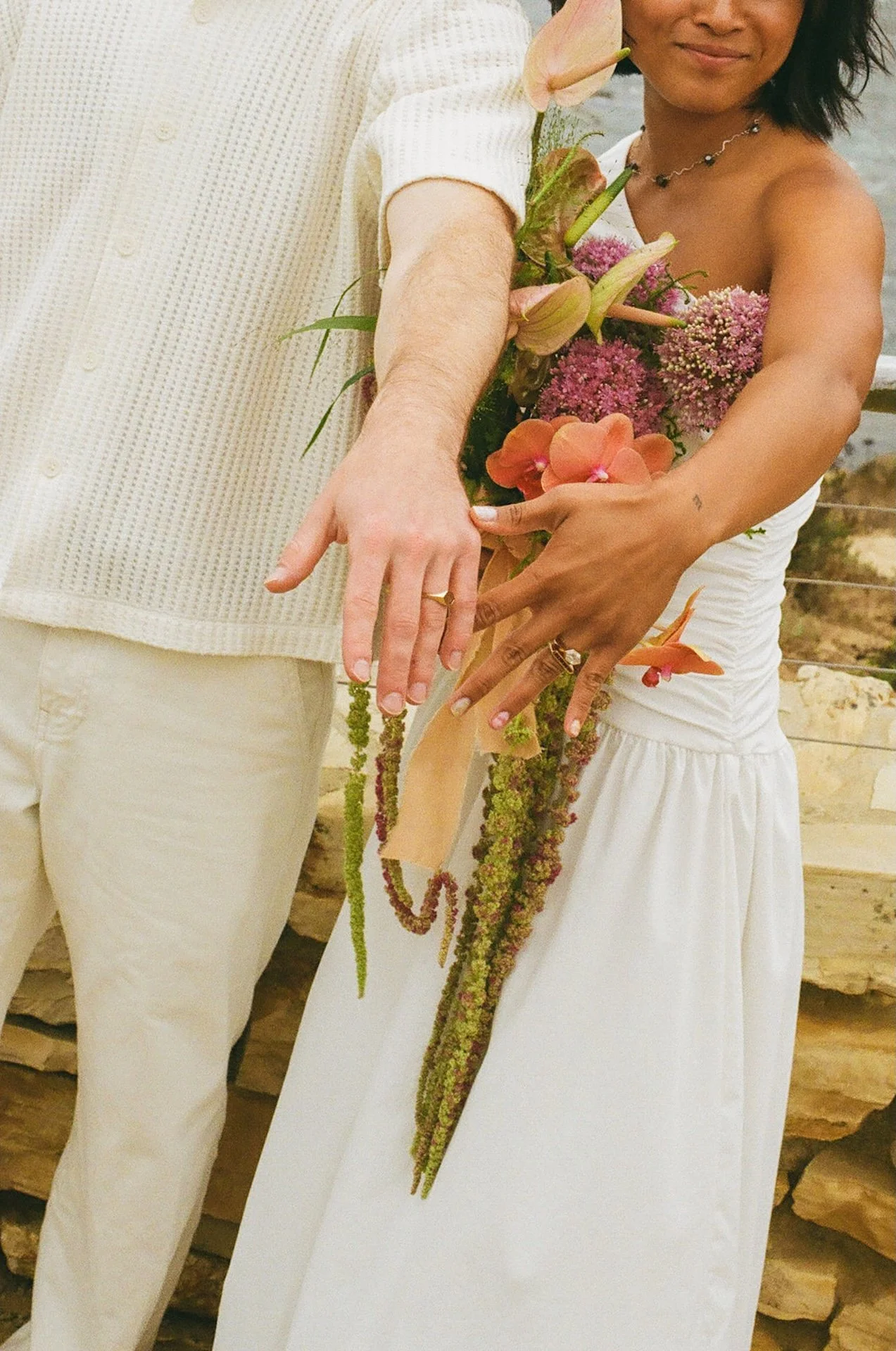 the bride and and groom holding their hands out to show off their wedding rings after their elopement on the beach