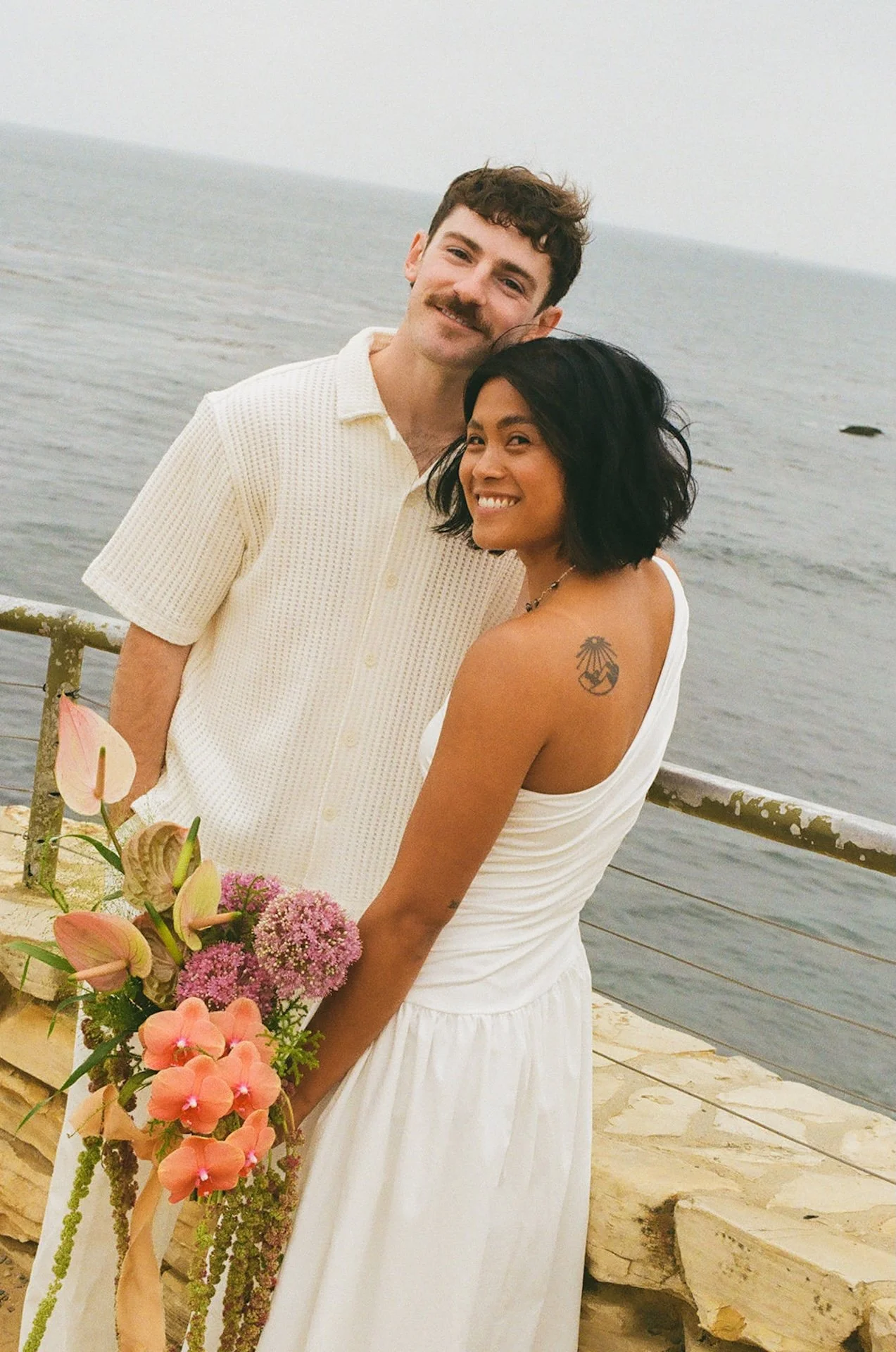 The bride and groom smiling with the California coast in the background during their elopement on the beach