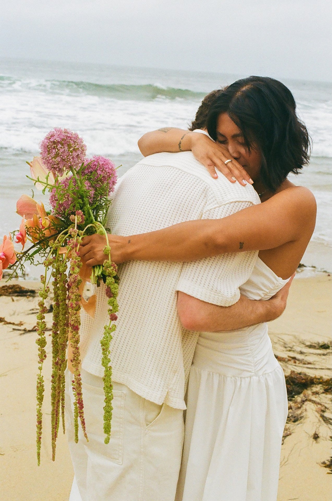 The bride and groom hugging and laughing during their couple portaits during their elopement on the beach