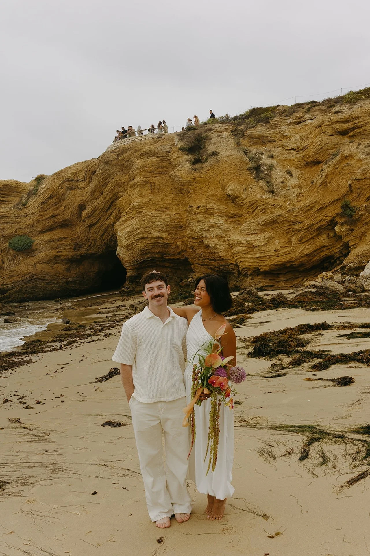 The bride and groom laughing together on the beach after their elopement ceremony on the beach