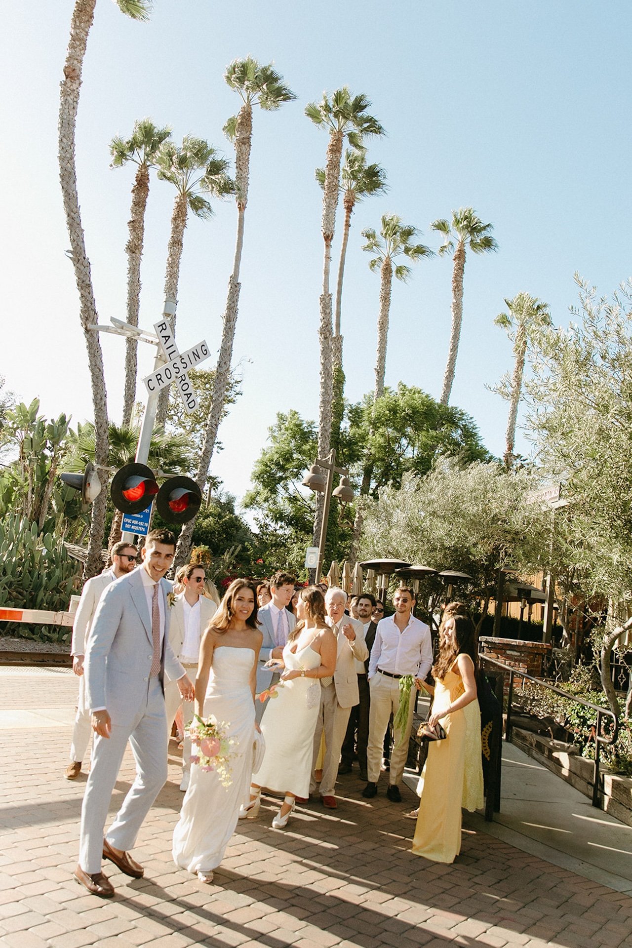Bride, groom, and the wedding party walking from the train station to their San Juan Capistrano Wedding Venue