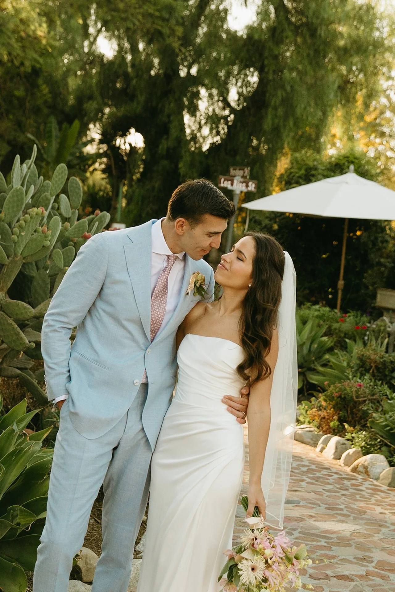 The bride and groom standing and smiling at each other during golden hour outside of their San Juan Capistrano Wedding Venue