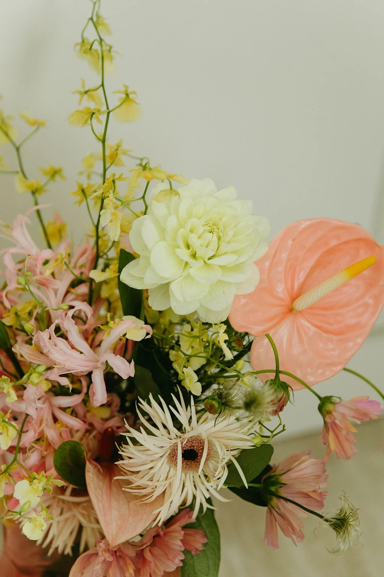 A close up photo of the bridal bouquet with white, pink, and yellow flowers.