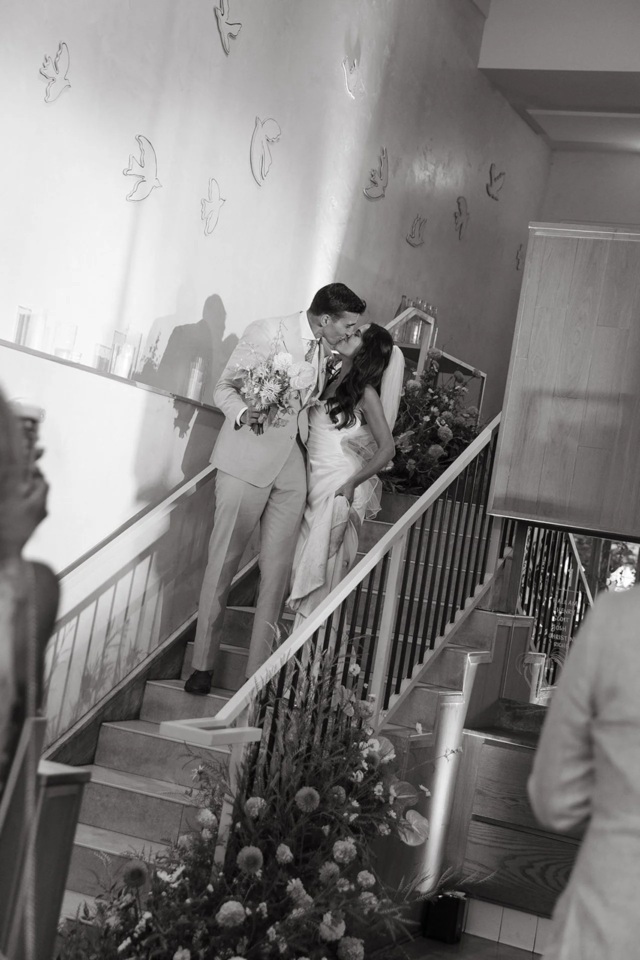 The bride and groom sharing a kiss on the stairs in the spotlight at the Mayfield during their San Juan Capistrano Wedding