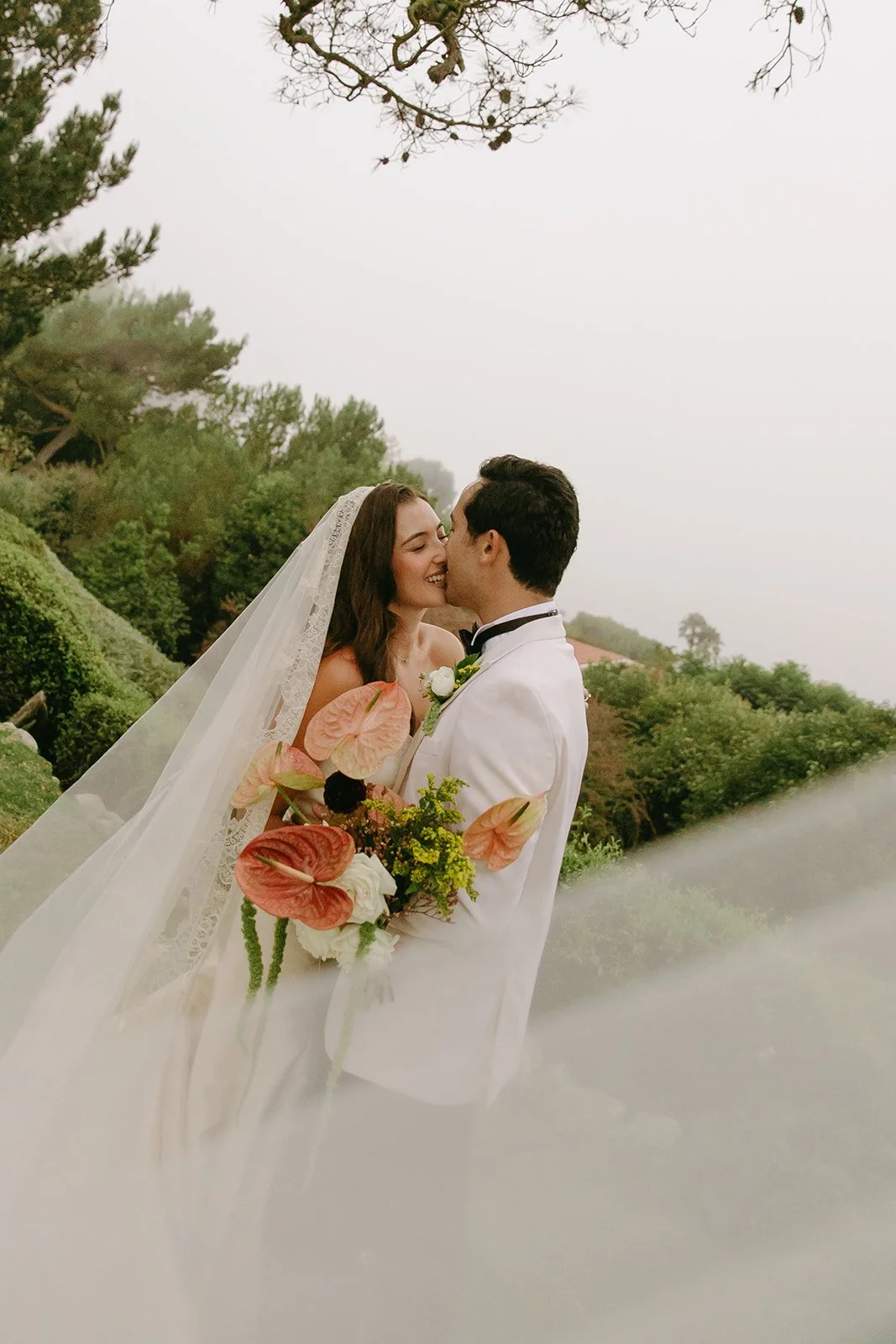 Soft, romantic portrait of the couple kissing with their bouquet in the foreground, captured by a Los Angeles wedding photographer.