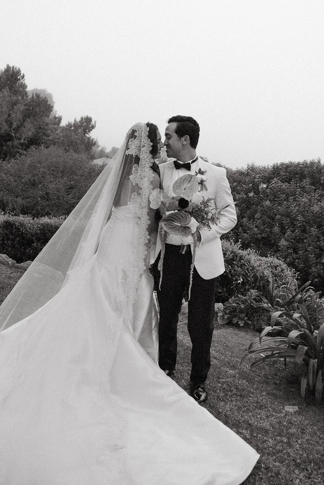 Black-and-white portrait of the couple standing close together with their bouquet during a La Venta Inn wedding.