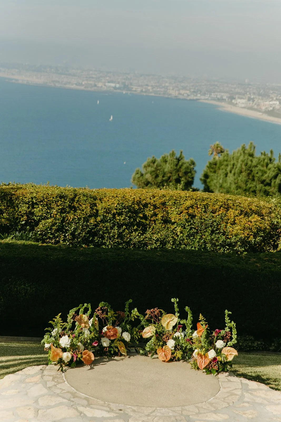 Floral ceremony arrangement placed along the stone aisle at a Palos Verdes wedding venue overlooking the ocean.