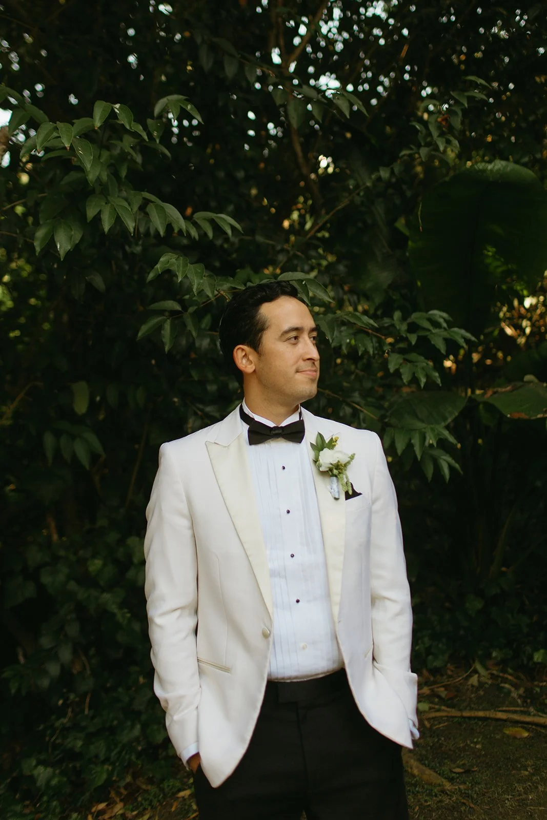 Groom standing alone in a white tuxedo jacket during portraits, captured by a Los Angeles wedding photographer.