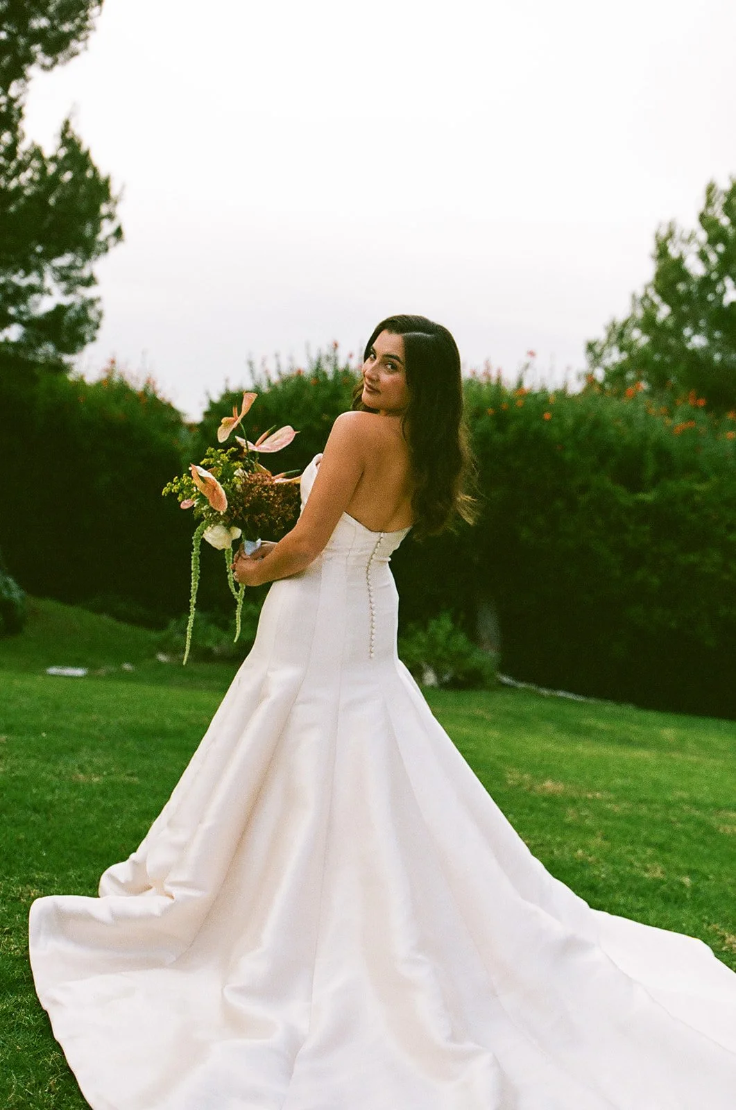 Bride holding her bouquet and looking back over her shoulder during golden-hour portraits at a Palos Verdes wedding venue.