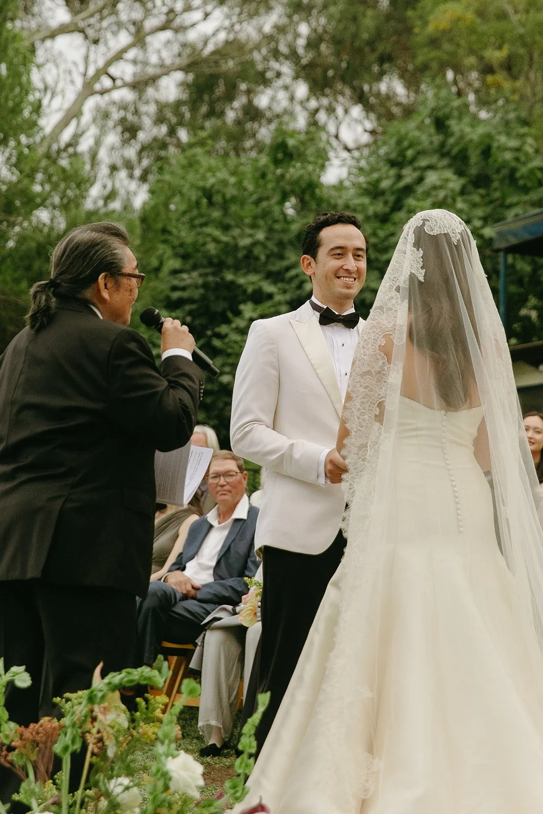 Groom smiling as he listens to vows while holding the bride’s hands.