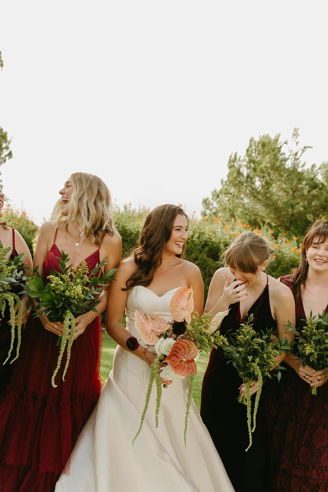 Bride laughing with her bridesmaids during portraits beneath the trees at a Historic Wedding Venue.