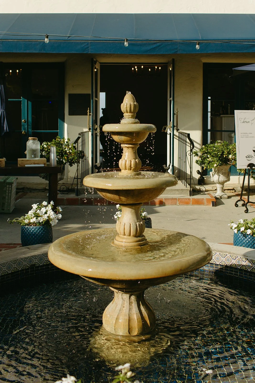 Outdoor fountain detail framed by potted florals and entry doors at the venue.