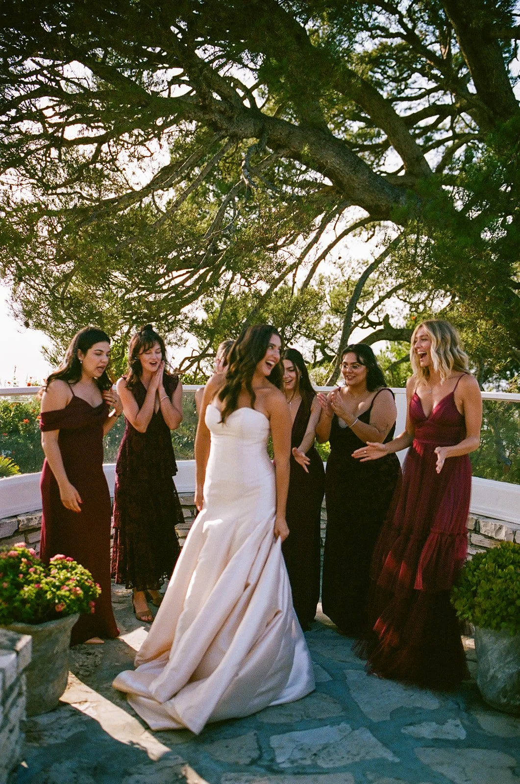 Bride laughing with her bridesmaids during portraits beneath the trees at a Historic Wedding Venue.