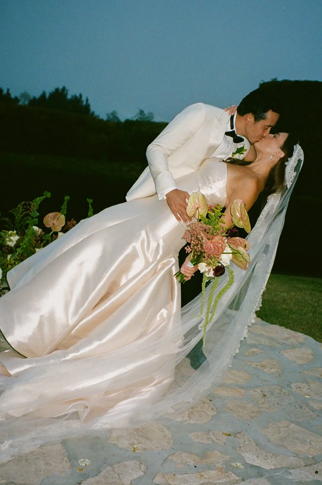 The groom dipping the bride into a kiss as her veil drapes across the stone ground at a Historic Wedding Venue.