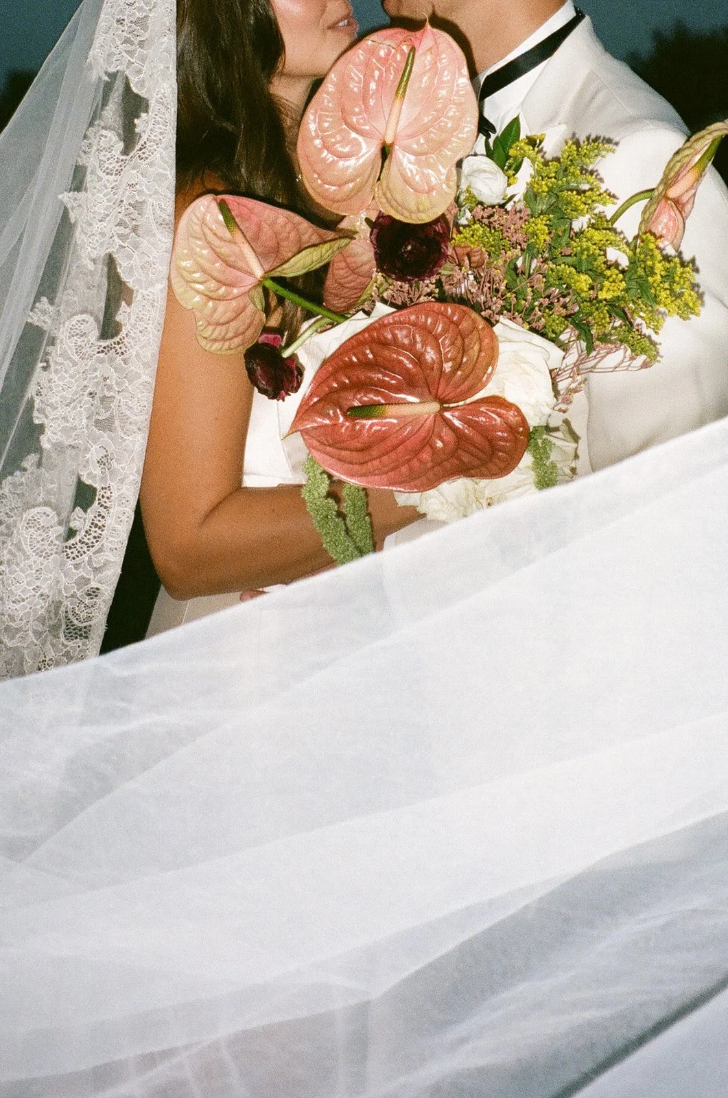 Close-up of the bride and groom leaning in behind a sculptural bouquet at a Historic Wedding Venue.