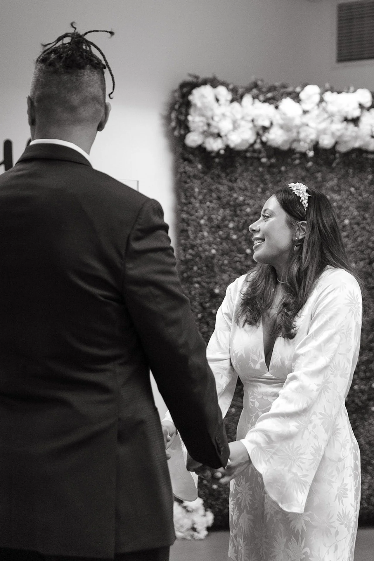 A black and white photo of the bride and groom standing in the courthouse holding hands and looking at the courthouse officiant during their Beverly Hills Courthouse Elopement