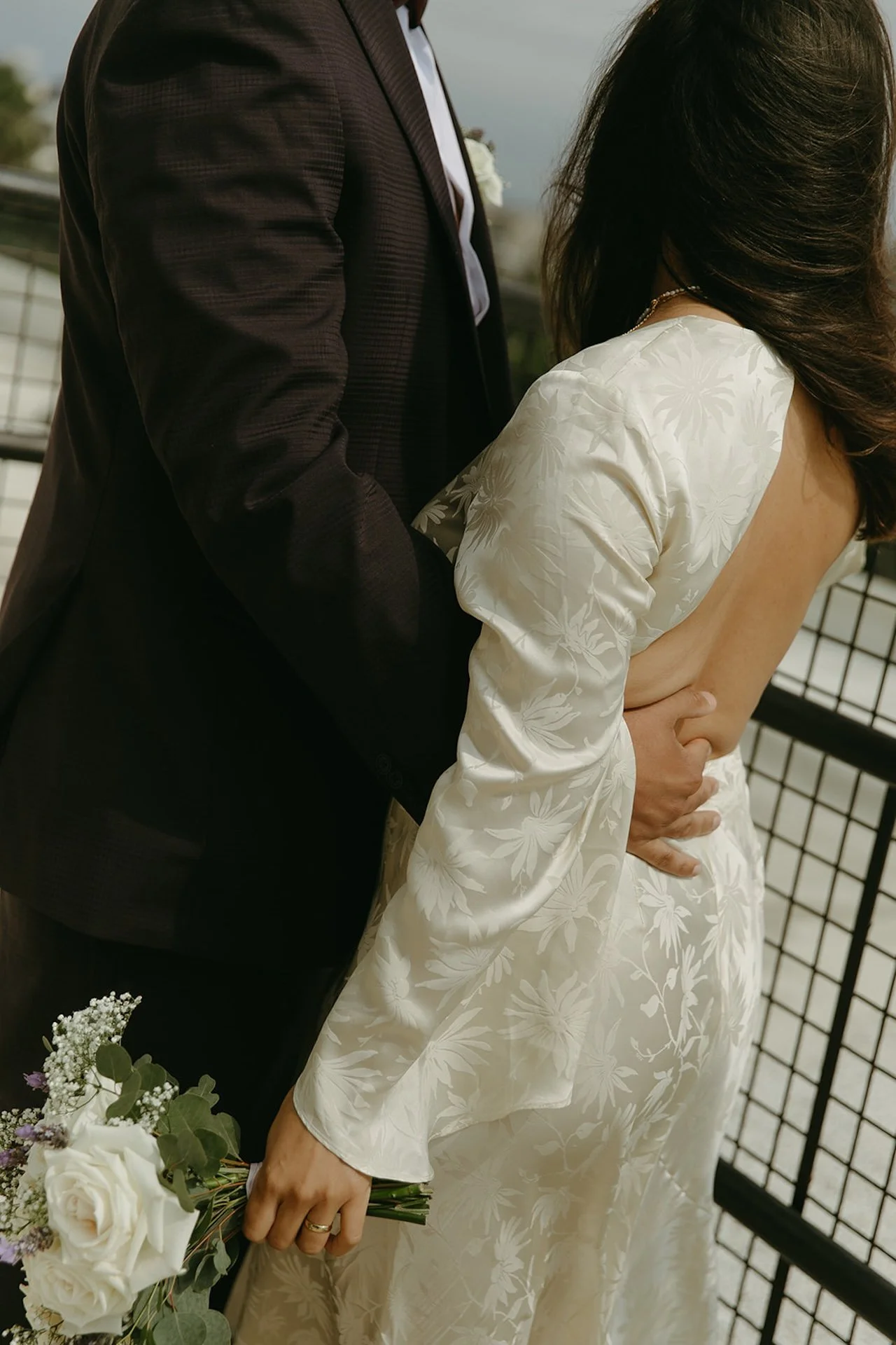 Candid closeup of the groom holding the brides waist as she holds her flowers
