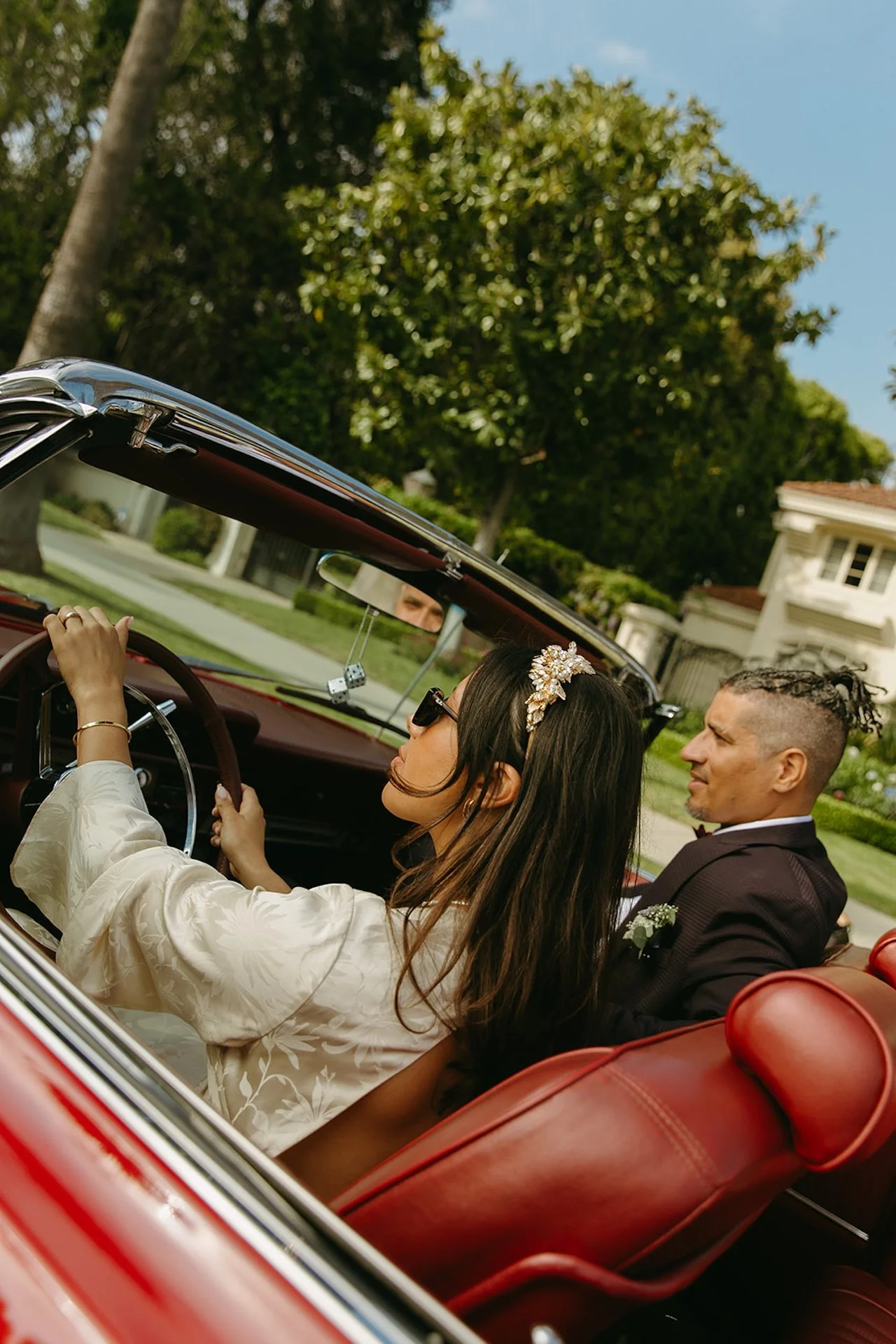 A editorial photo of the bride driving the groom in a red convertable