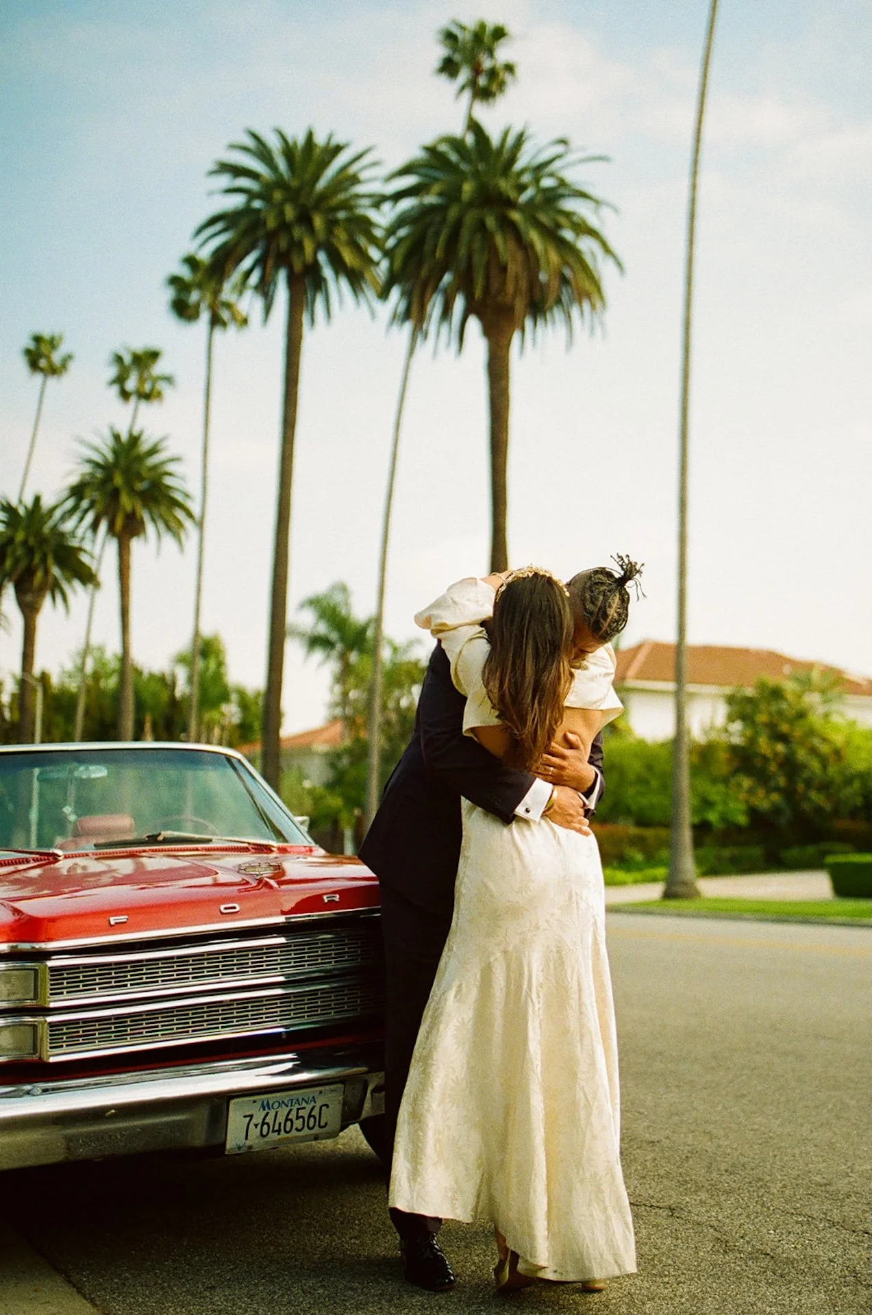 newlyweds hugging in front of a red convertable in Beverly Hills after their Beverly Hills Courthouse Elopement