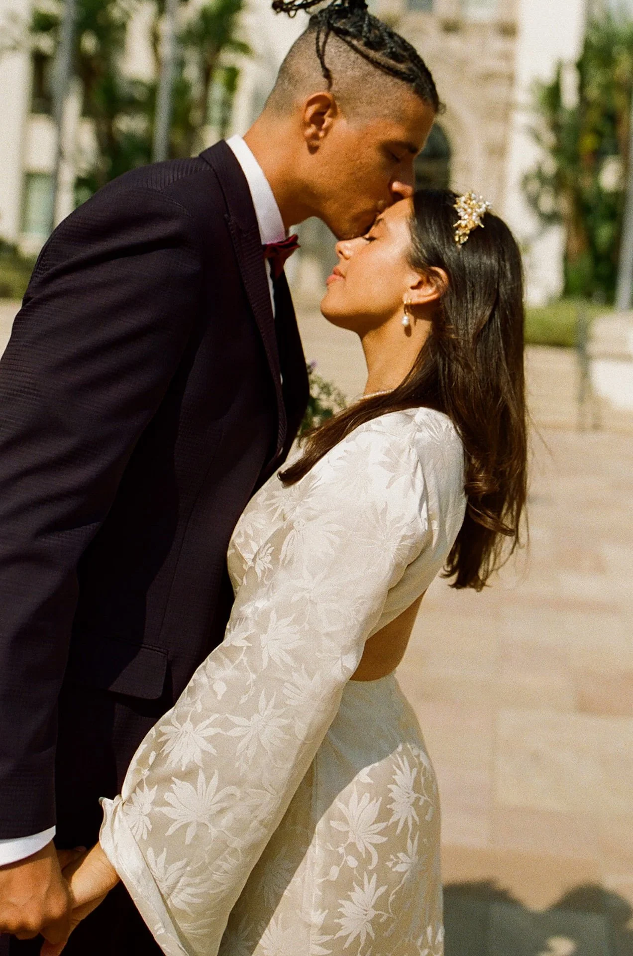 Candid photo of the groom kissing the brides forehead as they stand outside the Beverly Hills Courthouse after their ceremony