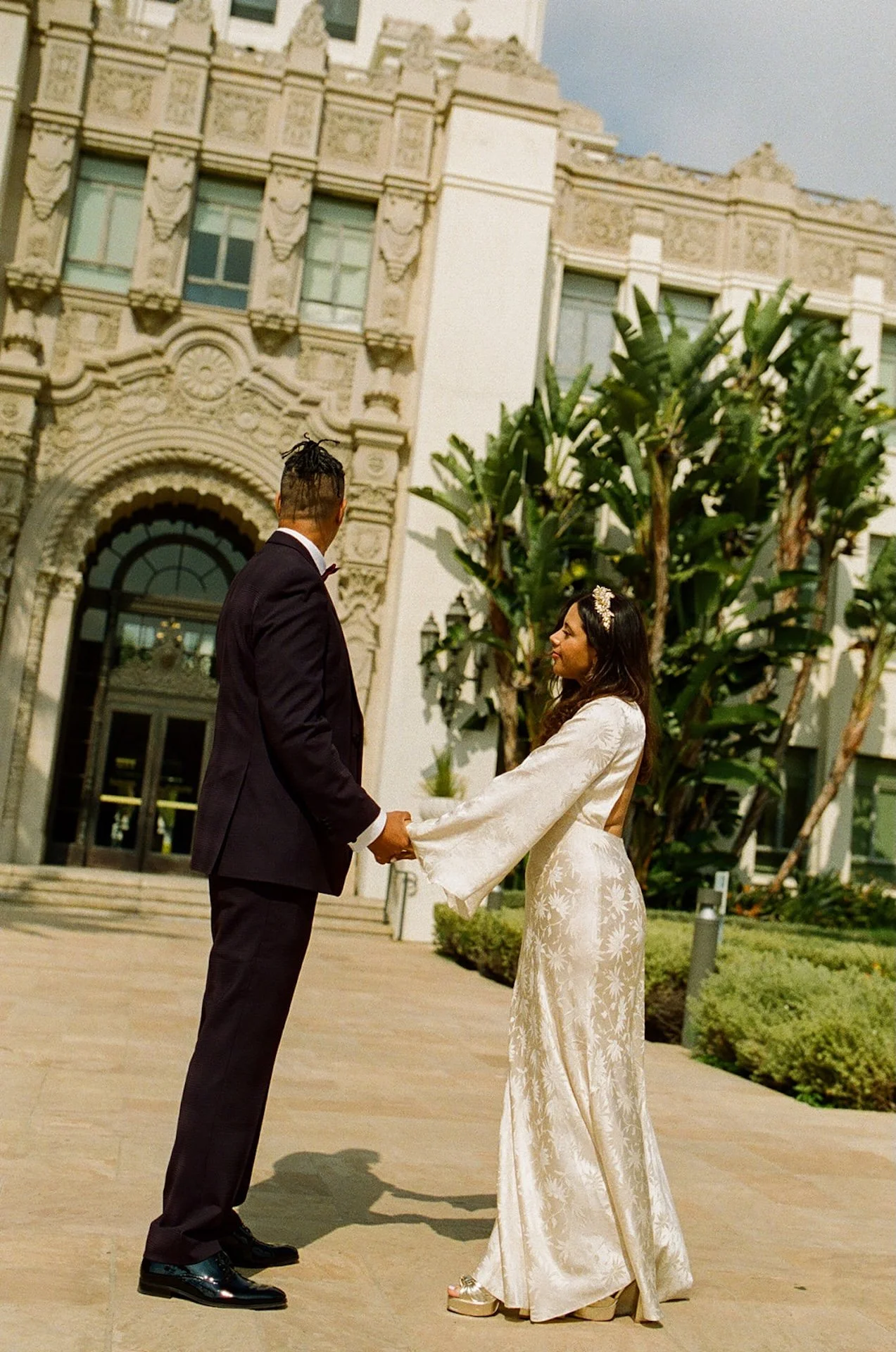 Newlyweds holding hands and standing in front of the Beverly Hills Courthouse after their ceremony in the courthouse