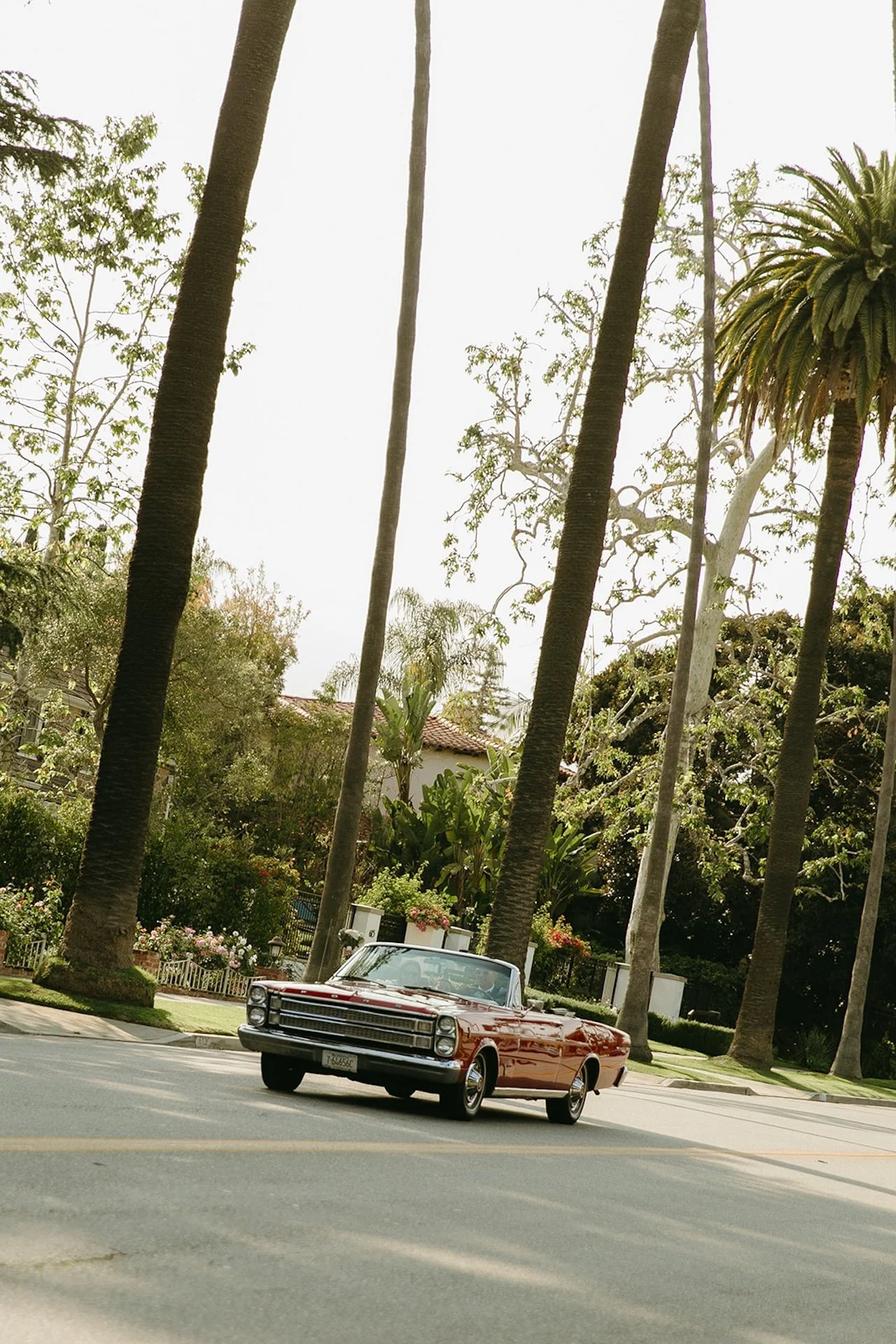 A red convertable driving down the round with newlyweds in it driving down a Beverly Hills street
