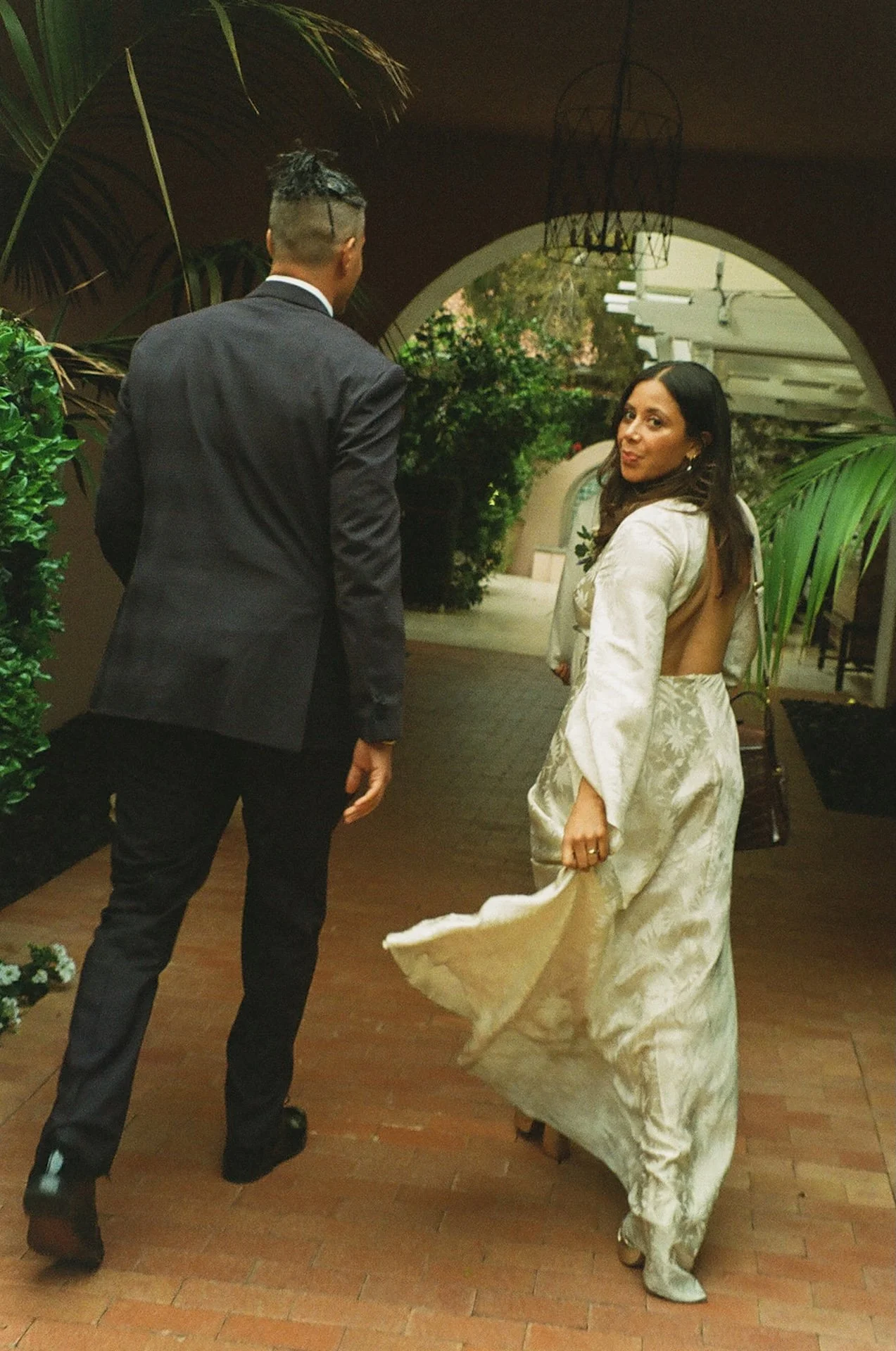 Newlyweds walking into their dinner celebration after their elopement. The bride holding her dress and looking back at the camera.