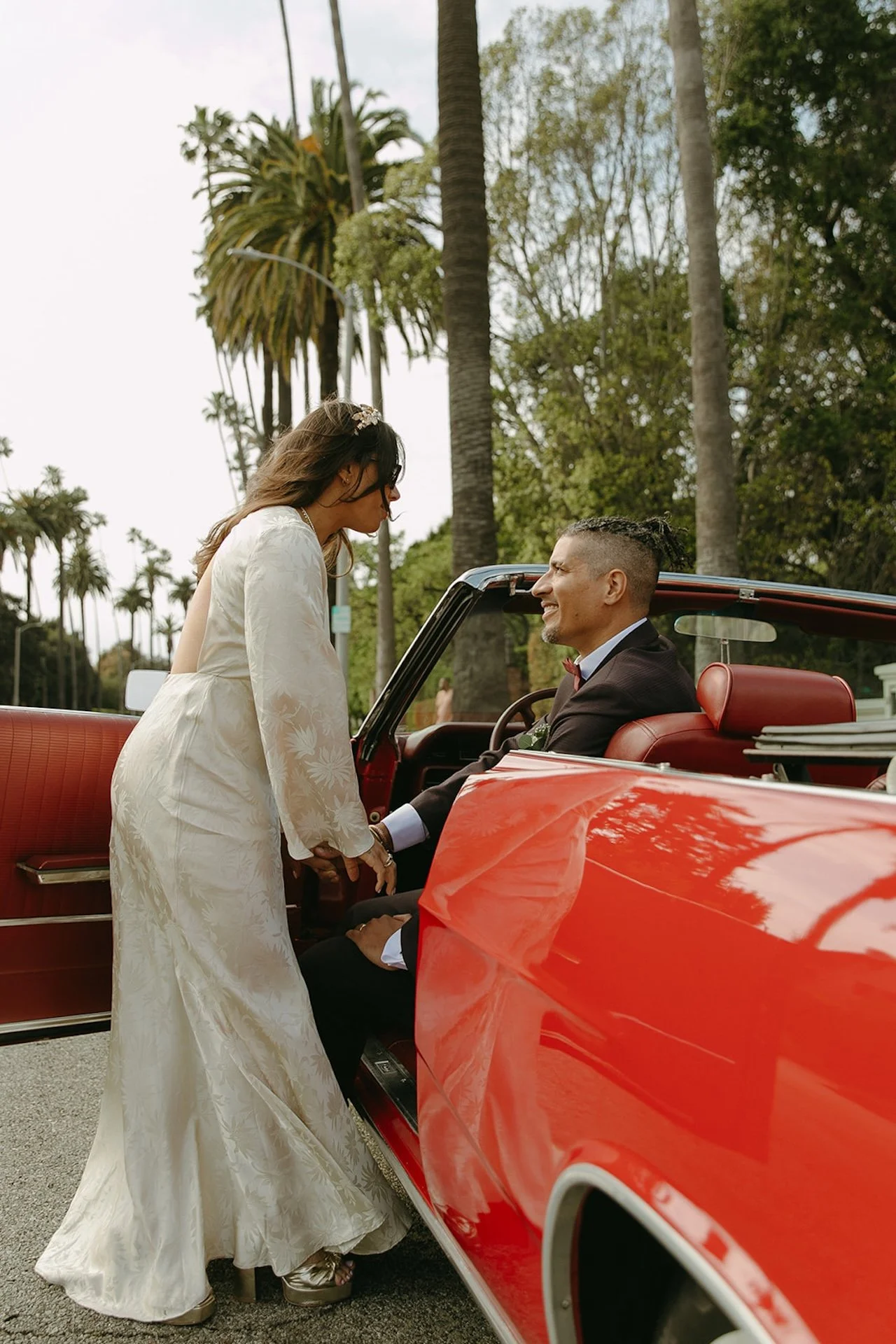 Bride and groom taking couple portraits with a red convertable after their Beverly Hills Courthouse Elopement