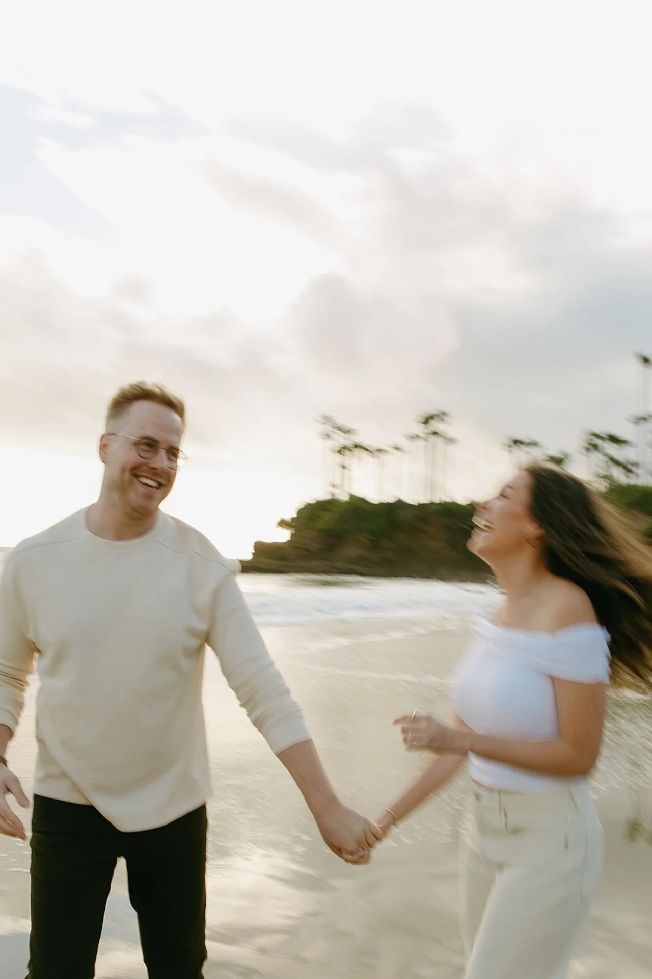Close-up of the couple walking hand in hand along the water’s edge, laughing together during laguna beach engagement photos at shaws cove laguna beach with soft coastal light.