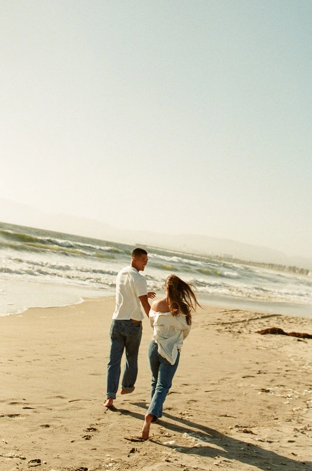 A candid couple walking together near the coast at one of the most relaxed Venice Beach Photoshoot Locations with soft afternoon light.