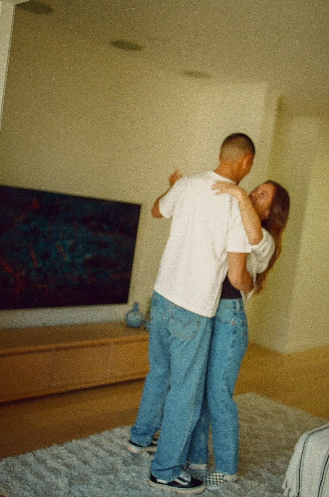 A couple dancing together in their living room during an intimate lifestyle engagement session.