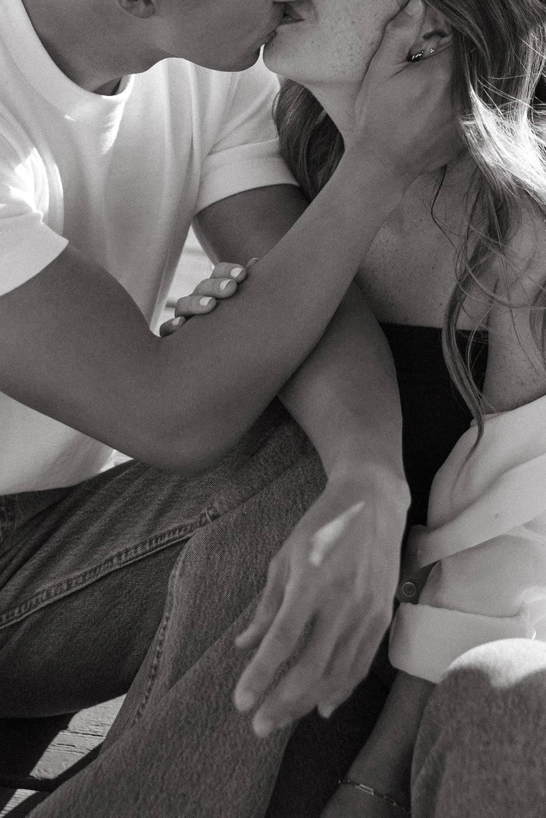 A closeup black and white photo of a couple leaning in to kiss each other.