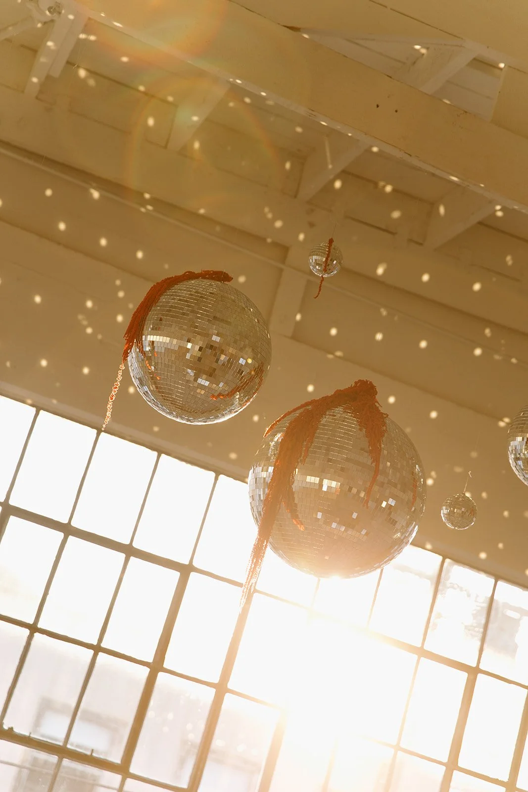 Disco balls hanging from the ceiling at The Revery LA catching the light and casting reflections across the walls.