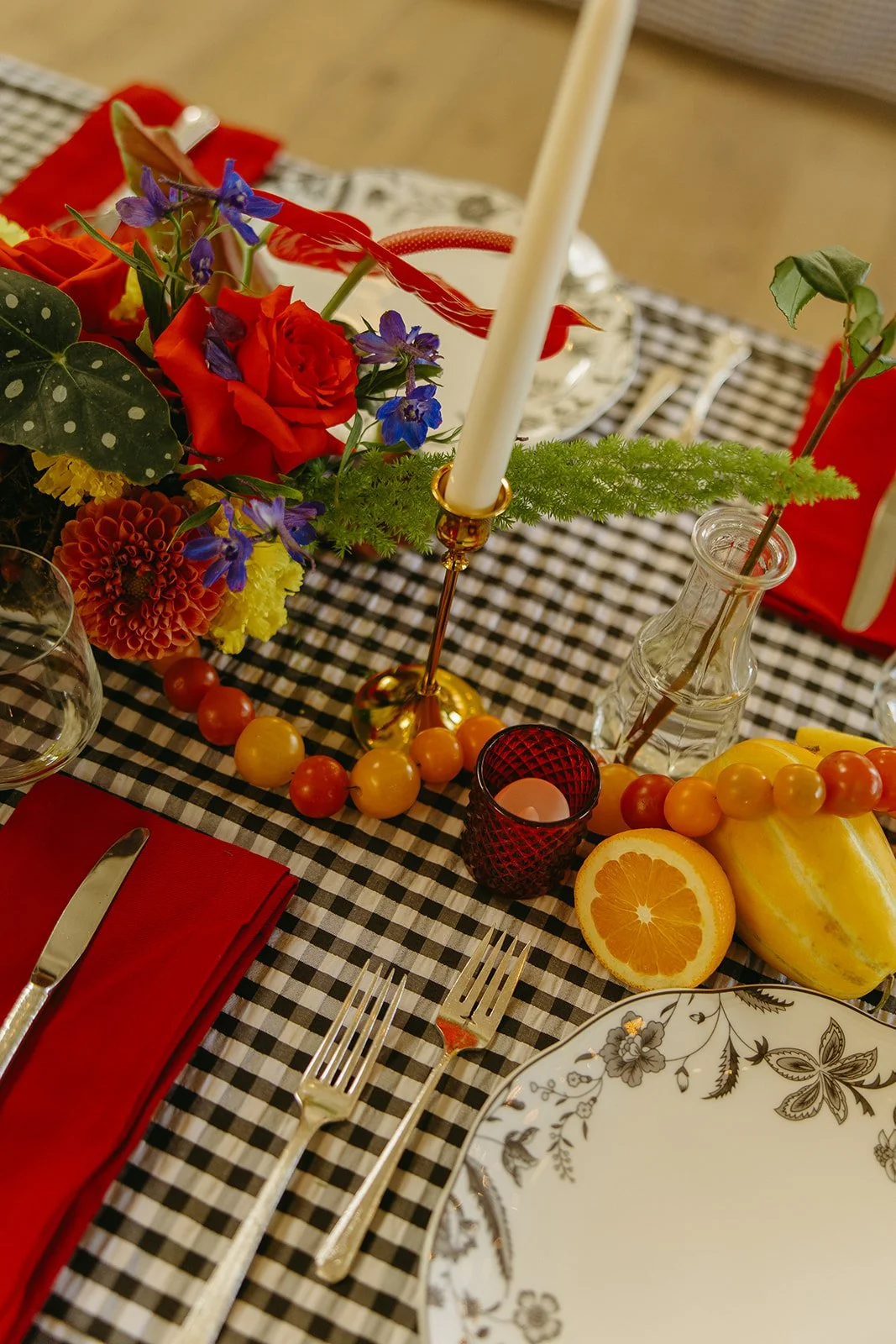 A close-up of colorful florals, candles, and table details arranged on a checkered tablecloth at The Revery LA.