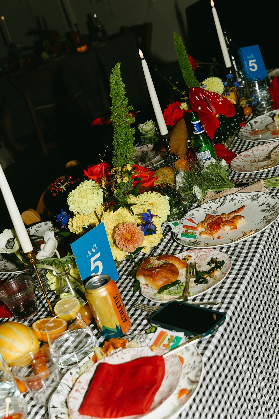 A lively dinner table scene at The Revery LA with florals, candles, drinks, and plates mid-meal during the reception.