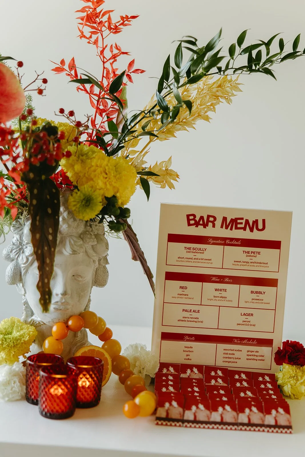 A styled bar setup at The Revery LA with colorful florals, citrus details, candles, and a custom bar menu on display.