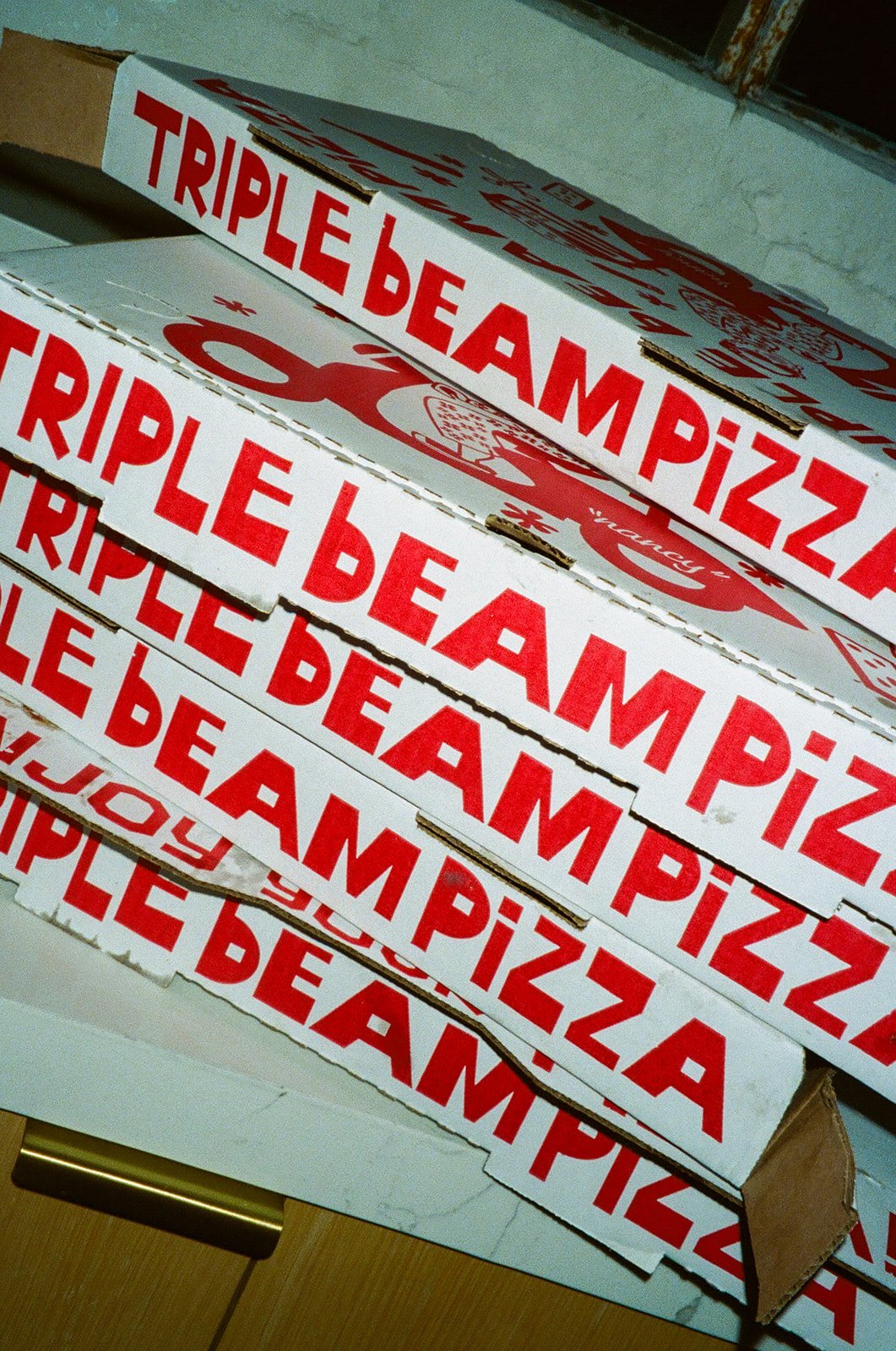 A stack of pizza boxes labeled “Triple Beam Pizza” set out during the reception at The Revery LA.