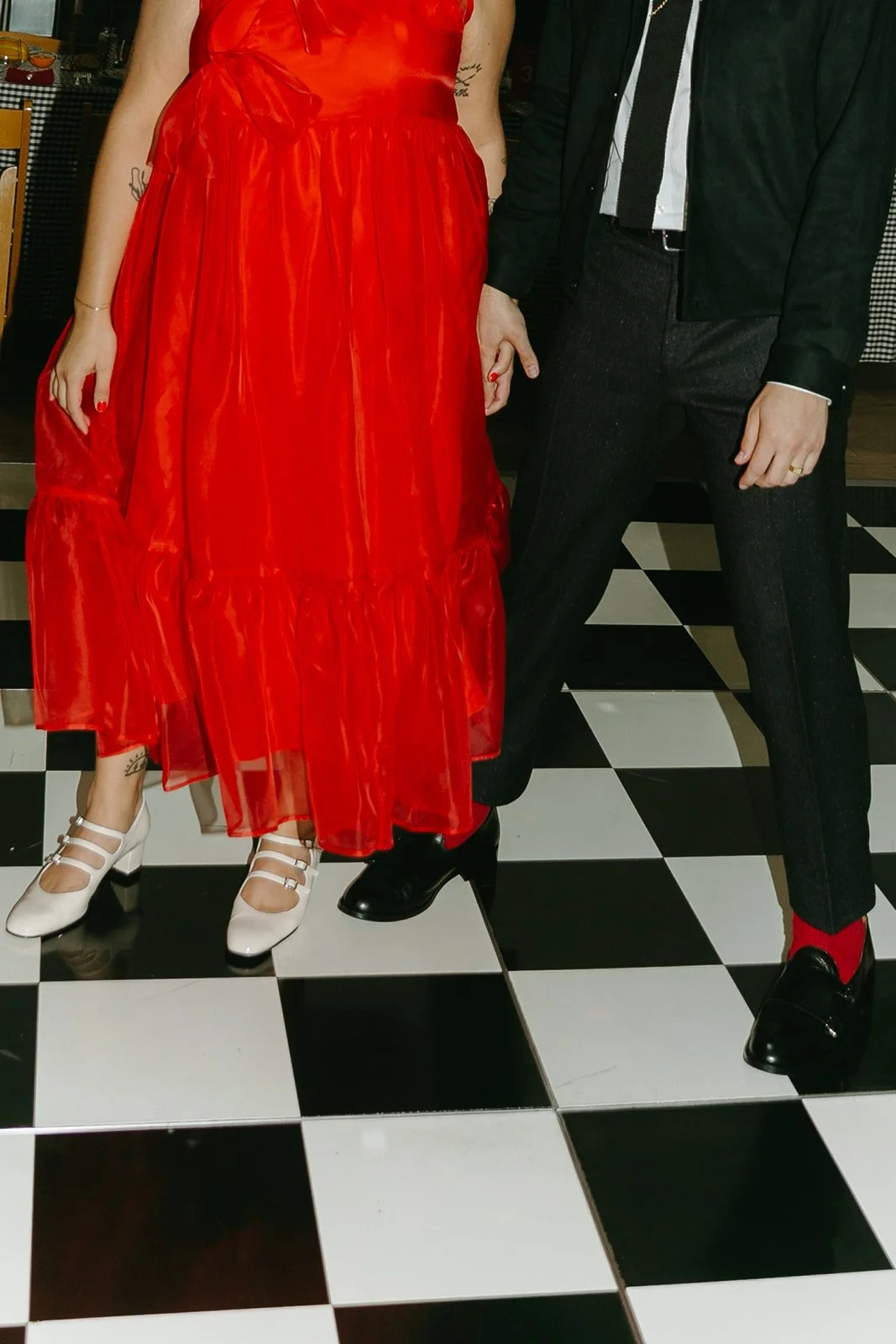 A close-up of the couple’s outfits and shoes as they stand together on the checkered dance floor at The Revery LA.